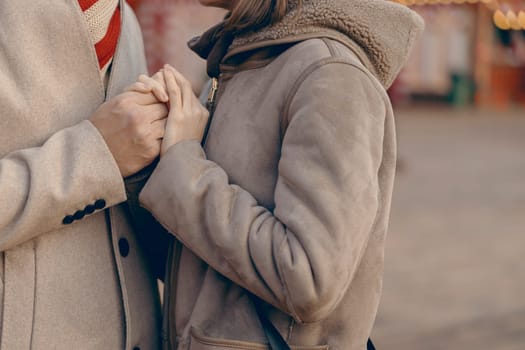 A close-up captures a couple's hands clasped together, symbolizing their strong bond during a festive winter day
