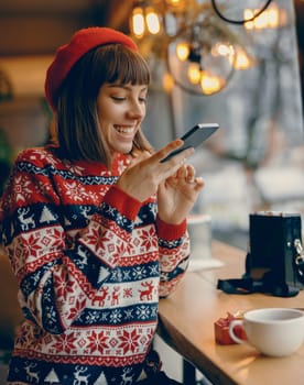 A joyous moment captured as a young woman with a bright smile examines a piece of jewelry, her festive sweater adding to the holiday atmosphere