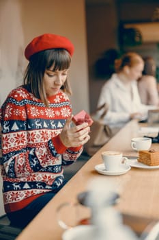 Contemplative woman with a festive gift, enjoying the holiday spirit in a cafe
