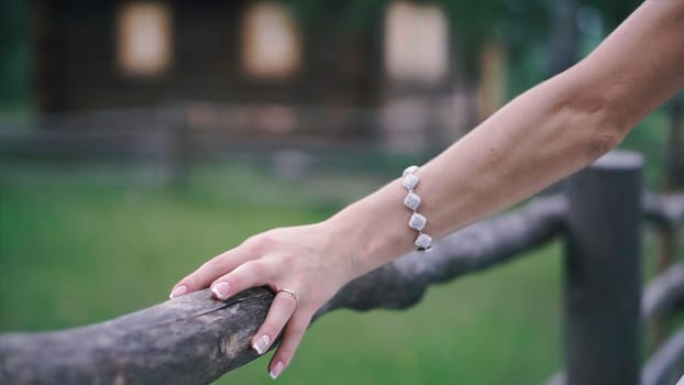 Close-up of bride's hands with on beautiful white wedding dress. Clip. Newlywed girl in outdoor near wooden fence.