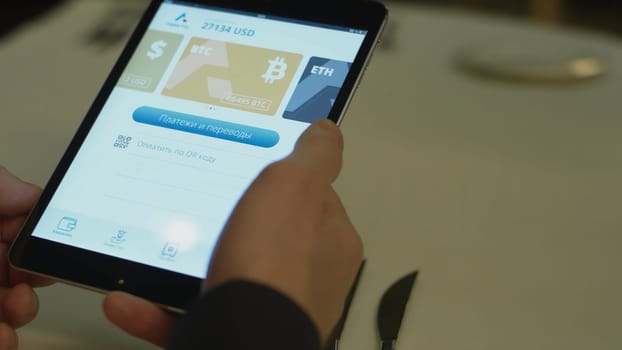 Paying a restaurant with bitcoin money with a tablet device wirelessly over credit card terminal. Receiving bitcoin money with a smartphone device wirelessly.