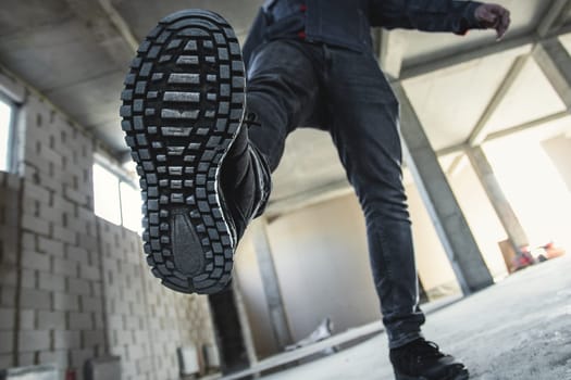 Close-up on construction safety shoes on a worker walking on a construction site.