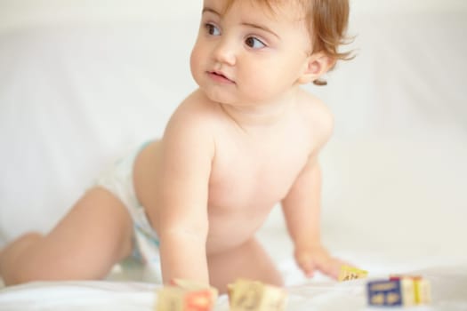 Baby, building blocks and playing on bed, education and learning for child development in bedroom. Sensory, alphabet and english or letters, care and toys for growth, coordination and cognitive skill.