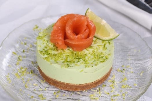 Timbale appetizer made from avocado, whipped with soft cheese cream and lime on short crust pastry with salmon. A great option for a holiday menu.