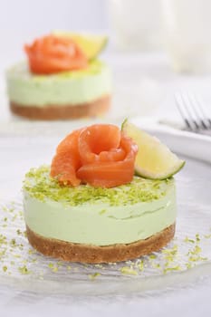 Timbale appetizer made from avocado, whipped with soft cheese cream and lime on short crust pastry with salmon. A great option for a holiday menu.