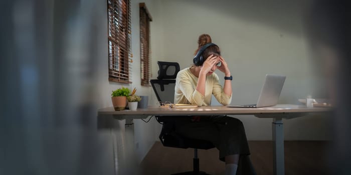 Asian women are stressed while working on laptop, Tired Asian businesswoman with headache at office feeling sick at work.