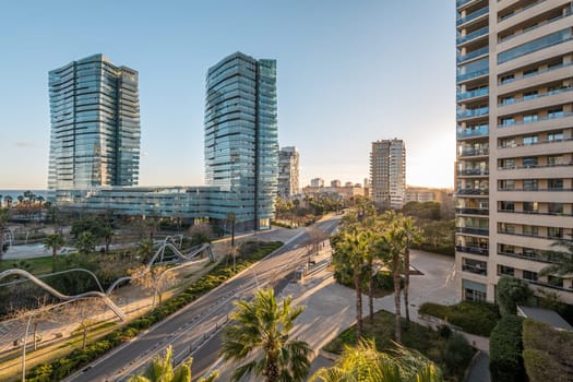Diagonal Mar area in Barcelona with skyscrapers and major road junctions. Modern city with developed infrastructure with palm trees at sunset