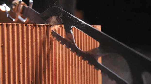 Close-up of automatic saw cutting cutting the brick in the dark workshop. Building and constructions concept