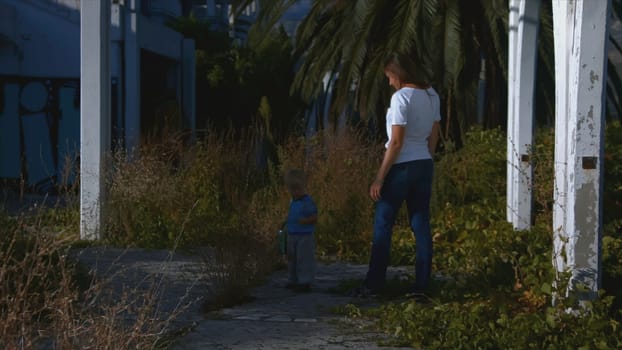 Woman follows child on walk in summer. Creative. Woman stands with child and watches him on walk. Woman walks with child in nature in summer in sunny day.