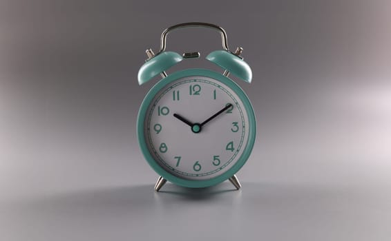 Close-up of single simple designed green retro clock on grey surface. Metal vintage clock on tiny legs stand. Time, timer, alarm, decor, rarity concept