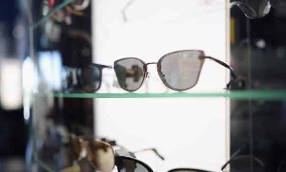 Stylish sunglasses lying on showcase in store closeup. Sale of fashion accessories concept