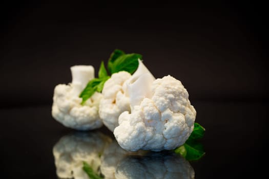 slices of raw small raw cauliflower isolated on black background