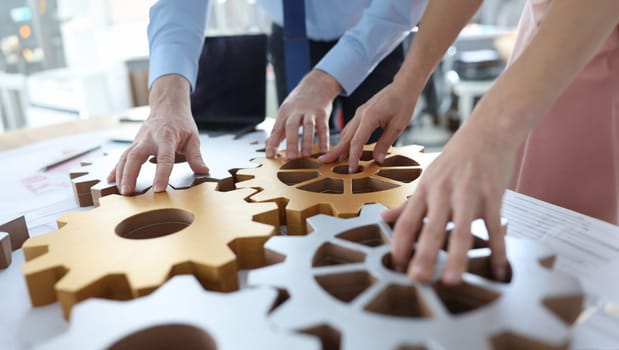 Business people stacking metal gears in office closeup. Brainstorming concept