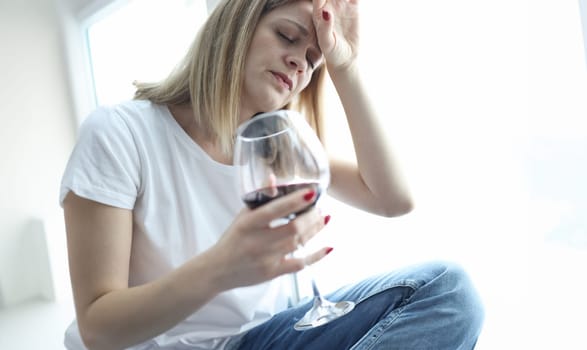 Tired woman with glass of red wine holding her head. Psychological problems concept