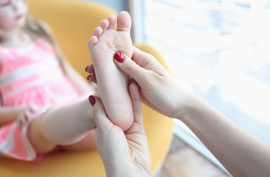 Doctor orthopedist examining feet of little girl closeup. Correction of flat feet in children concept