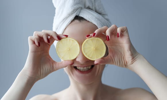Young woman holding lemons in front of her eyes. Skin care concept