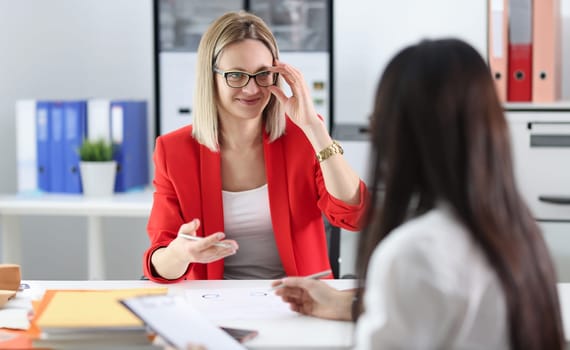 Business woman with glasses communicating with colleague at table. Employment concept