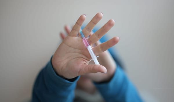Drug syringe lying in mans hand closeup. Drug addiction concept