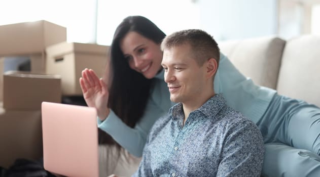 Man and woman looking at laptop screen and waving hand. Remote communication online concept