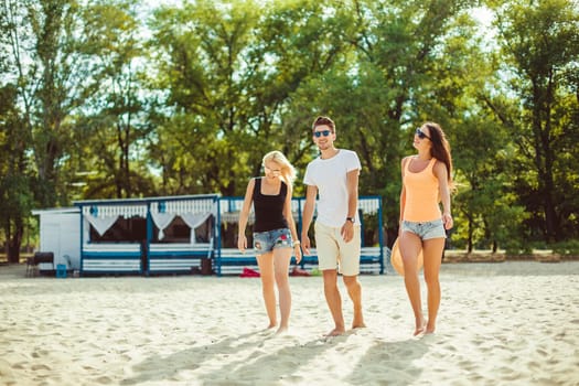 Young funny guys in sunglasses on the beach. Friends together. Summer bar is on background.