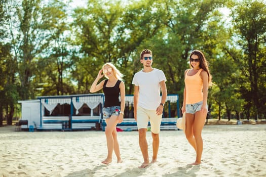 Young funny guys in sunglasses on the beach. Friends together. Summer bar is on background.