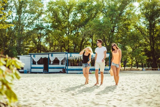 Young funny guys in sunglasses on the beach. Friends together. Summer bar is on background.