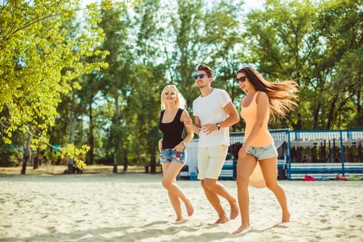 Young funny guys in sunglasses on the beach. Friends together. Summer bar is on background.