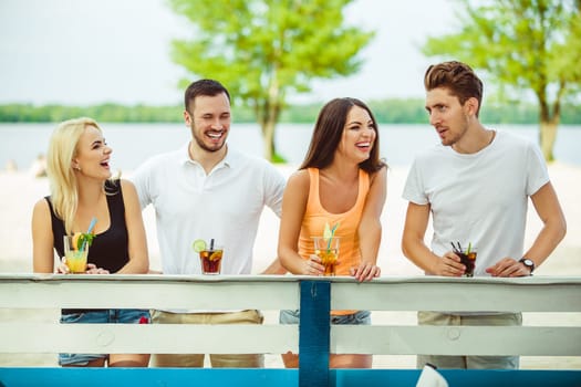 Friends having fun at the bar outdoors, drinking cocktails. Summer bar