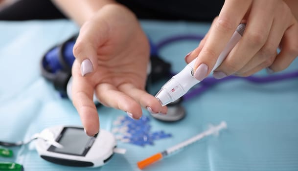 Woman drawing blood with lancet at home closeup. Blood glucose control in diabetes mellitus concept