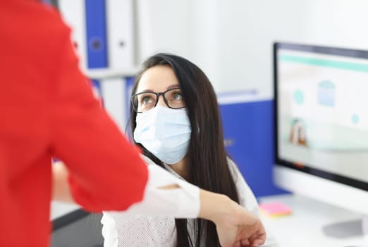 Woman in protective mask greeting each other with her elbows. Security measures during covid19 pandemic concept