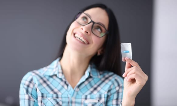 Contented woman holding blister with one capsule in her hands. Emergency hormonal contraception concept