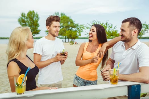 Friends having fun at the bar outdoors, drinking cocktails. Summer bar