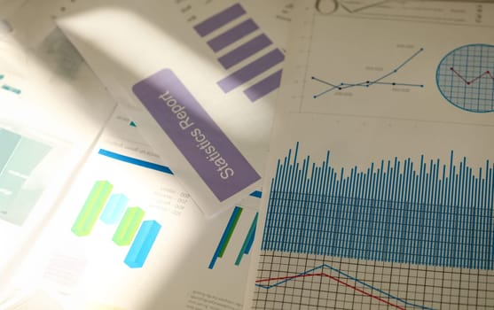 Close-up of pile of documents used to analyze successful corporation investment. Significant charts and graphs lying on table in office. Reports sale concept