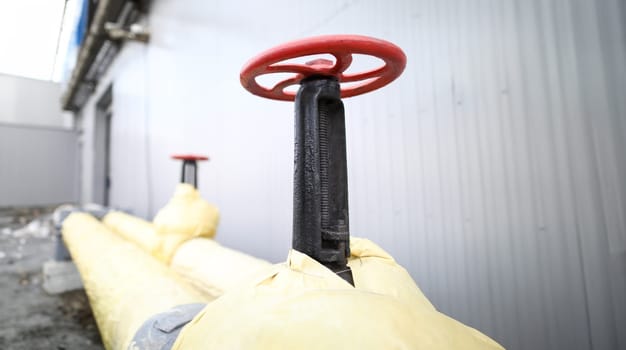 Huge industrial red valve on main heating pipeline closeup