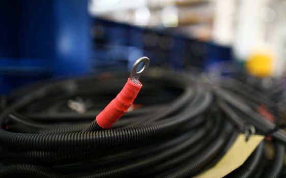 Piece of electric cable with terminal lying at warehouse closeup