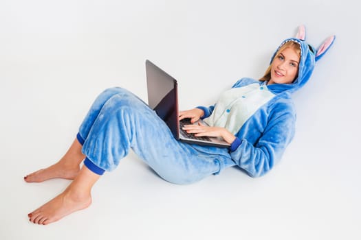 girl in pajamas with a laptop lying on the floor. studying or doing online shopping. work from home. Satisfied and smiling