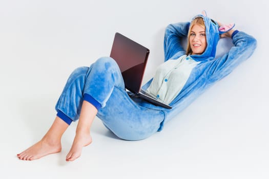 girl in pajamas with a laptop lying on the floor. studying or doing online shopping. work from home. Satisfied and smiling