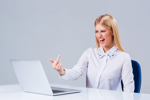 Young businesswoman working at laptop computer. dissatisfied showing middle finger