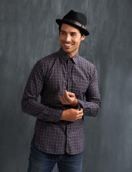 Fashion, happy and man on gray background with confidence in trendy style, clothes and casual outfit. Smile, handsome and face of person on texture wall with accessory, pride and positive attitude.