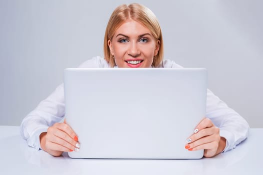 Young businesswoman working at laptop computer. hiding behind the monitor contented happy girl