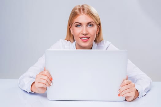 Young businesswoman working at laptop computer. hiding behind the monitor contented happy girl