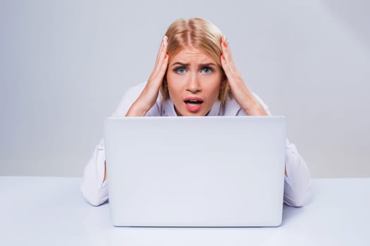 Young businesswoman working at laptop computer. hiding behind the monitor. frustrated, spiteful woman in shock
