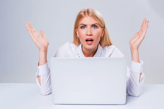 Young businesswoman working at laptop computer. hiding behind the monitor. frustrated, spiteful woman in shock