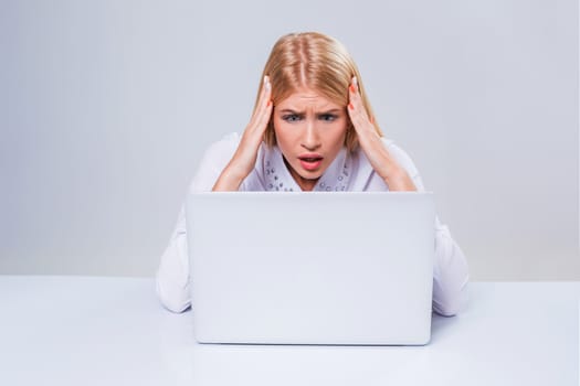 Young businesswoman working at laptop computer. hiding behind the monitor. frustrated, spiteful woman in shock