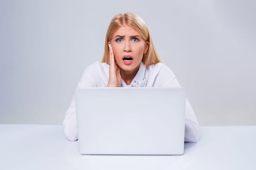 Young businesswoman working at laptop computer. hiding behind the monitor. frustrated, spiteful woman in shock