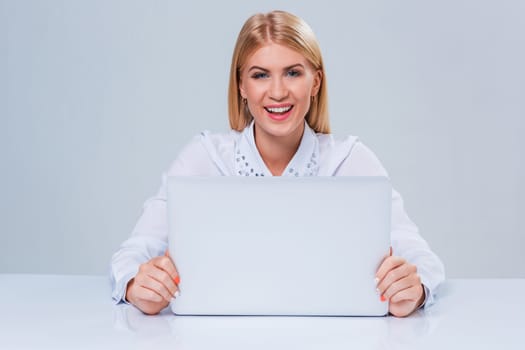 Young businesswoman working at laptop computer. hiding behind the monitor contented happy girl