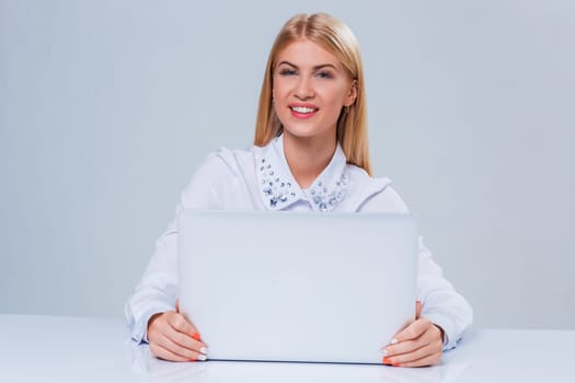 Young businesswoman working at laptop computer. hiding behind the monitor contented happy girl