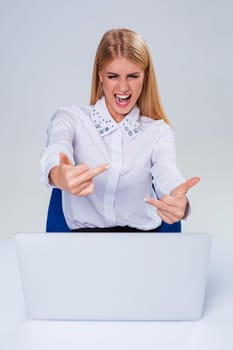 Young businesswoman working at laptop computer. hiding behind the monitor. frustrated, spiteful woman in shock showing middle finger