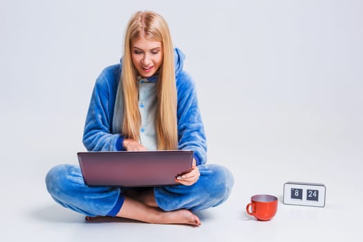 girl in pajamas with a laptop lying on the floor. studying or doing online shopping. work from home. Satisfied and smiling in the morning