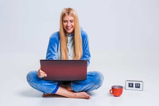 girl in pajamas with a laptop lying on the floor. studying or doing online shopping. work from home. Satisfied and smiling in the morning